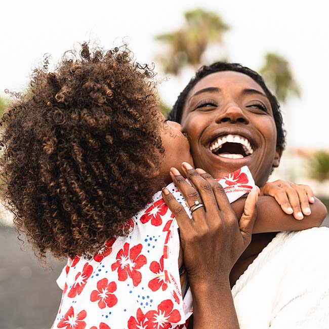 A black women hugging her daughter and smiling after general dentistry 