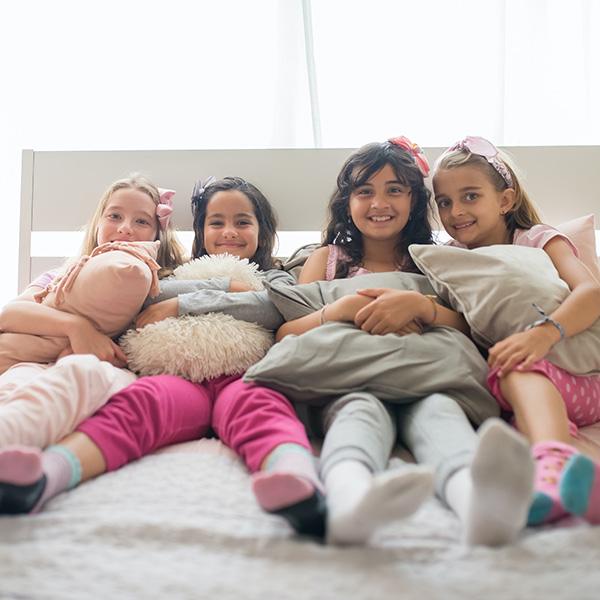 Children Smiling While Sitting On A Bed